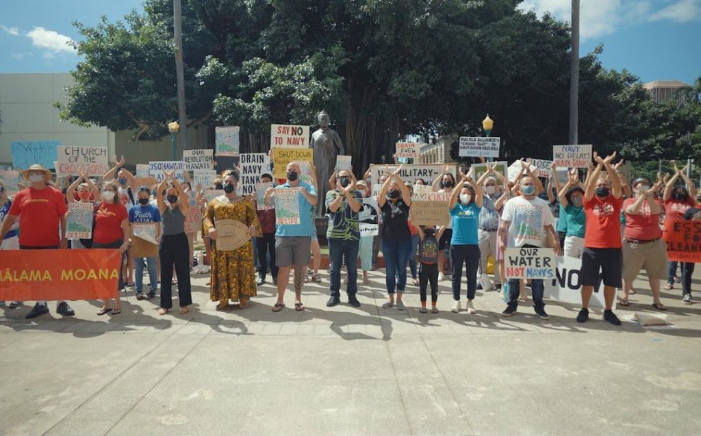 O‘ahu Water Protectors hold signs: "Say No to Navy," "Shut Down Red Hill," "Our Water Not Navy's", Ola i ka wai"